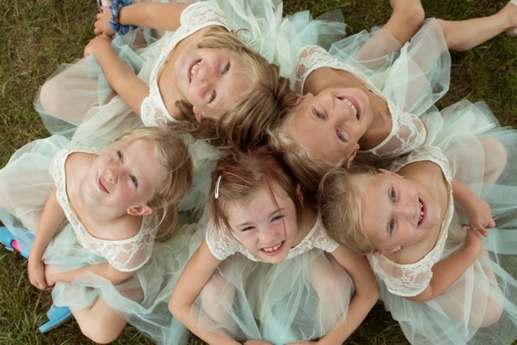 Young Oxbow Dance students in tulle costumes smiling together in a circle